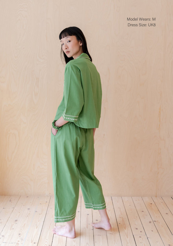 Side view of TBCo cotton and linen pyjamas in green with embroidered trim details and relaxed fit, shown on wooden floor