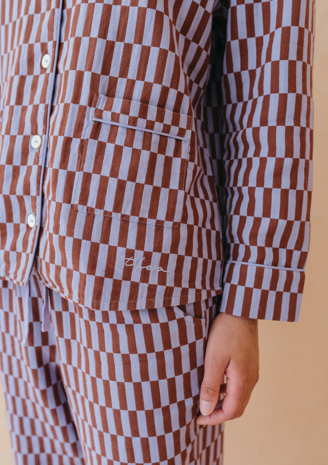 Close-up detail of TBCo Cotton Pyjamas in Lilac Checkerboard pattern, showing piped pocket and white buttons on cotton fabric
