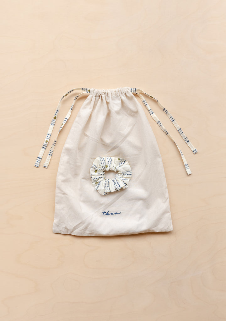 TBCo matching cotton drawstring bag and scrunchie for Cotton Pyjamas in Navy Ditsy floral lying flat on a wooden surface