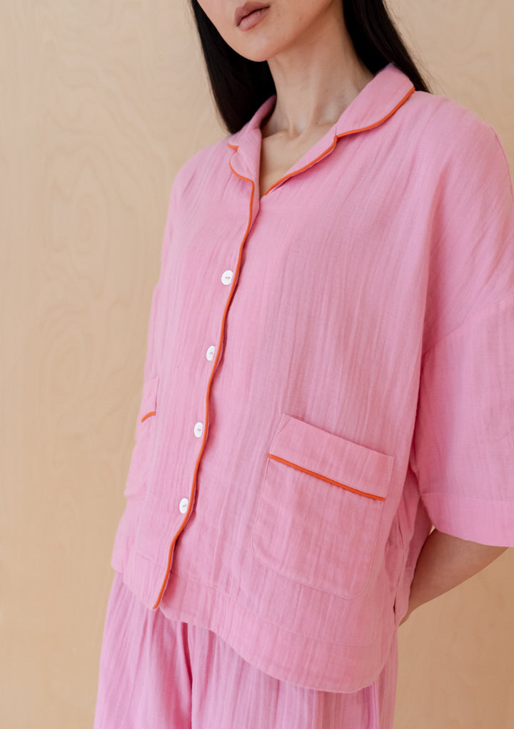Pink cotton pyjamas from TBCo featuring scalloped edges and orange piping, with matching scrunchie and gauze fabric details