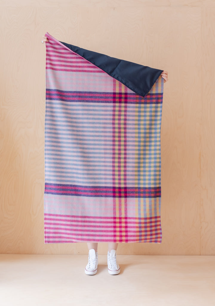 TBCo recycled wool picnic blanket in pink micro gingham pattern, featuring waterproof backing and portable roll-up design