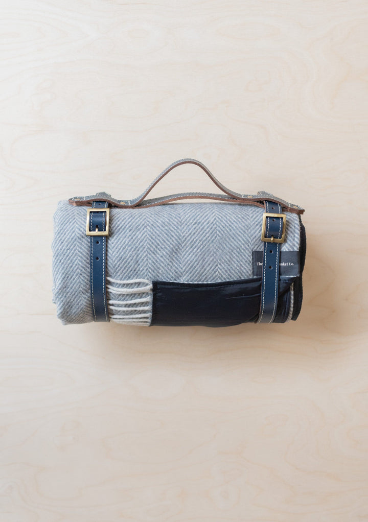 TBCo Recycled Wool Picnic Blanket in charcoal grey herringbone pattern with leather straps, rolled for transport