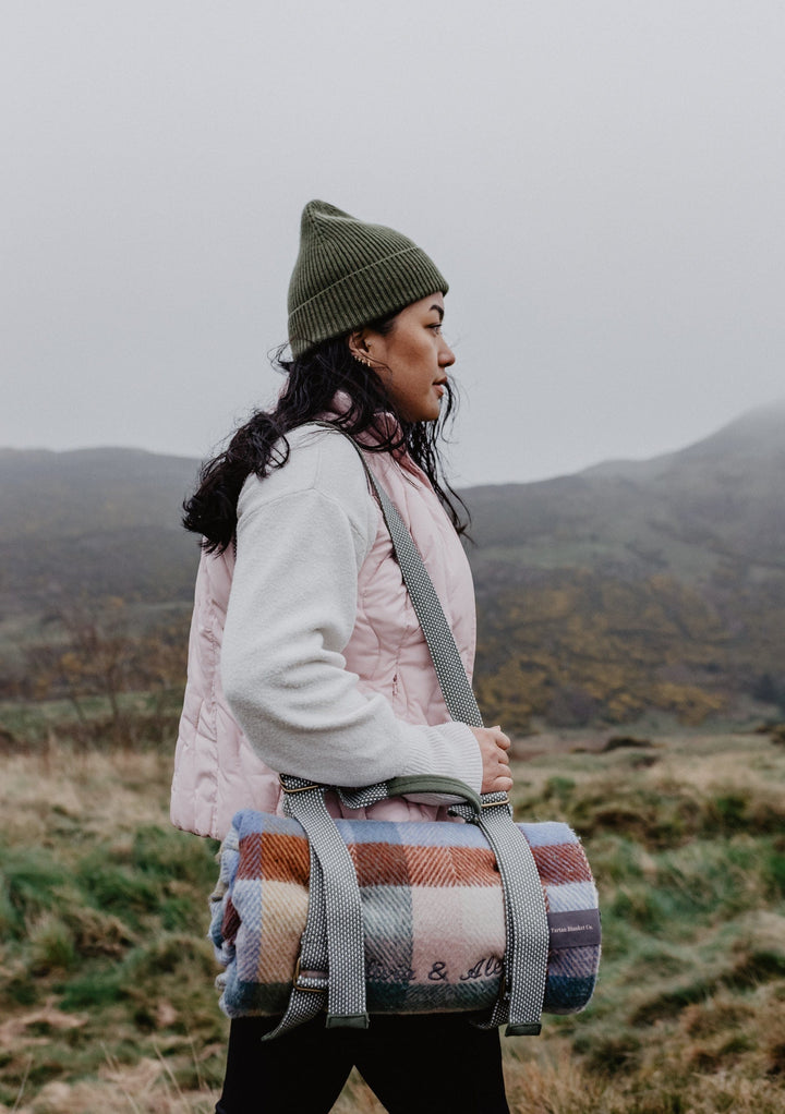 TBCo wool picnic blankets with carrier and should strap arranged in a scenic outdoor setting, showcasing their soft texture and vibrant patterns. Perfect for alfresco dining, relaxing in nature, or stylish outdoor gatherings.