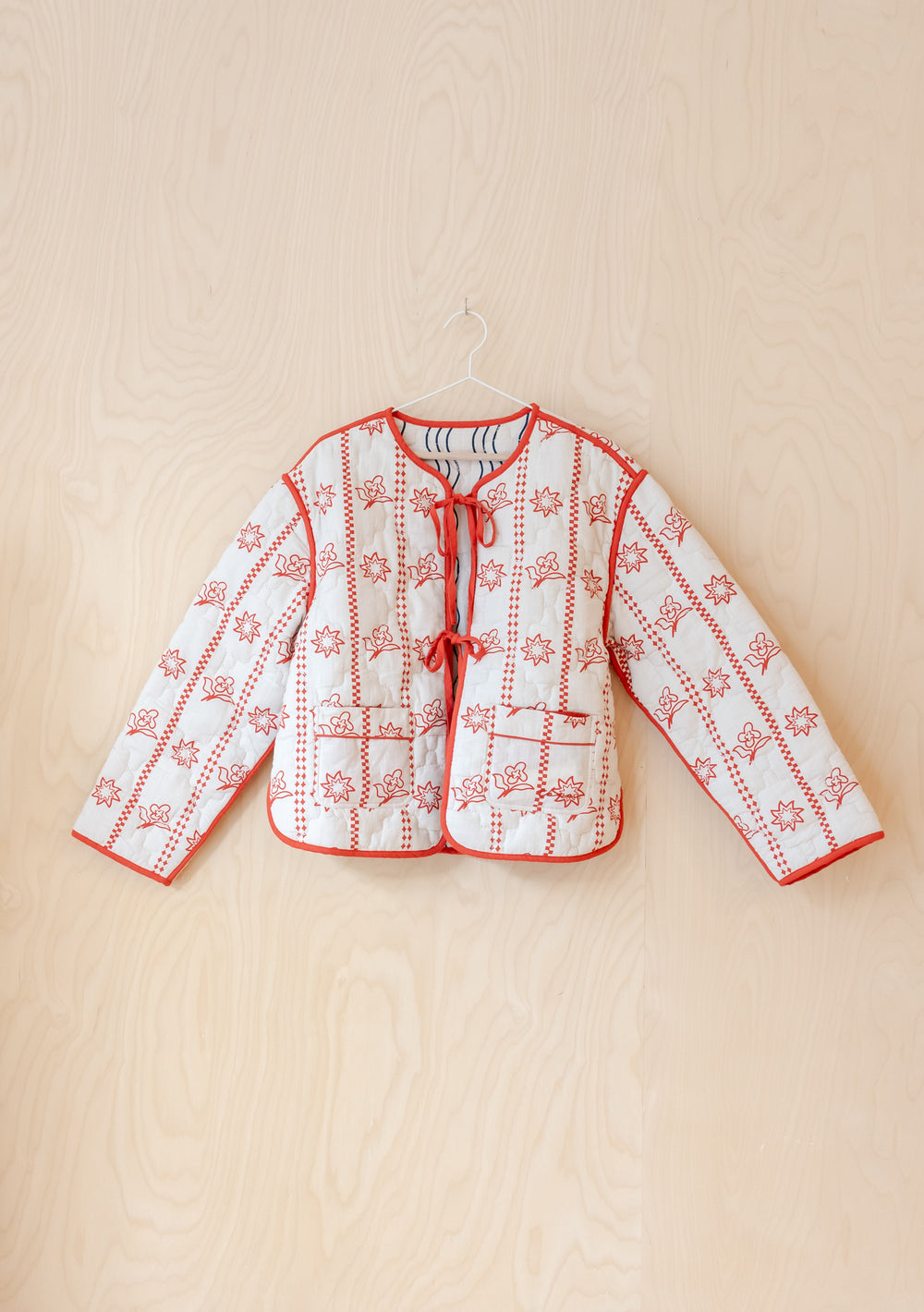 TBCo Quilted Cotton Jacket in Reversible Flora Wave shown in cream with red floral quilting pattern and front tie closures