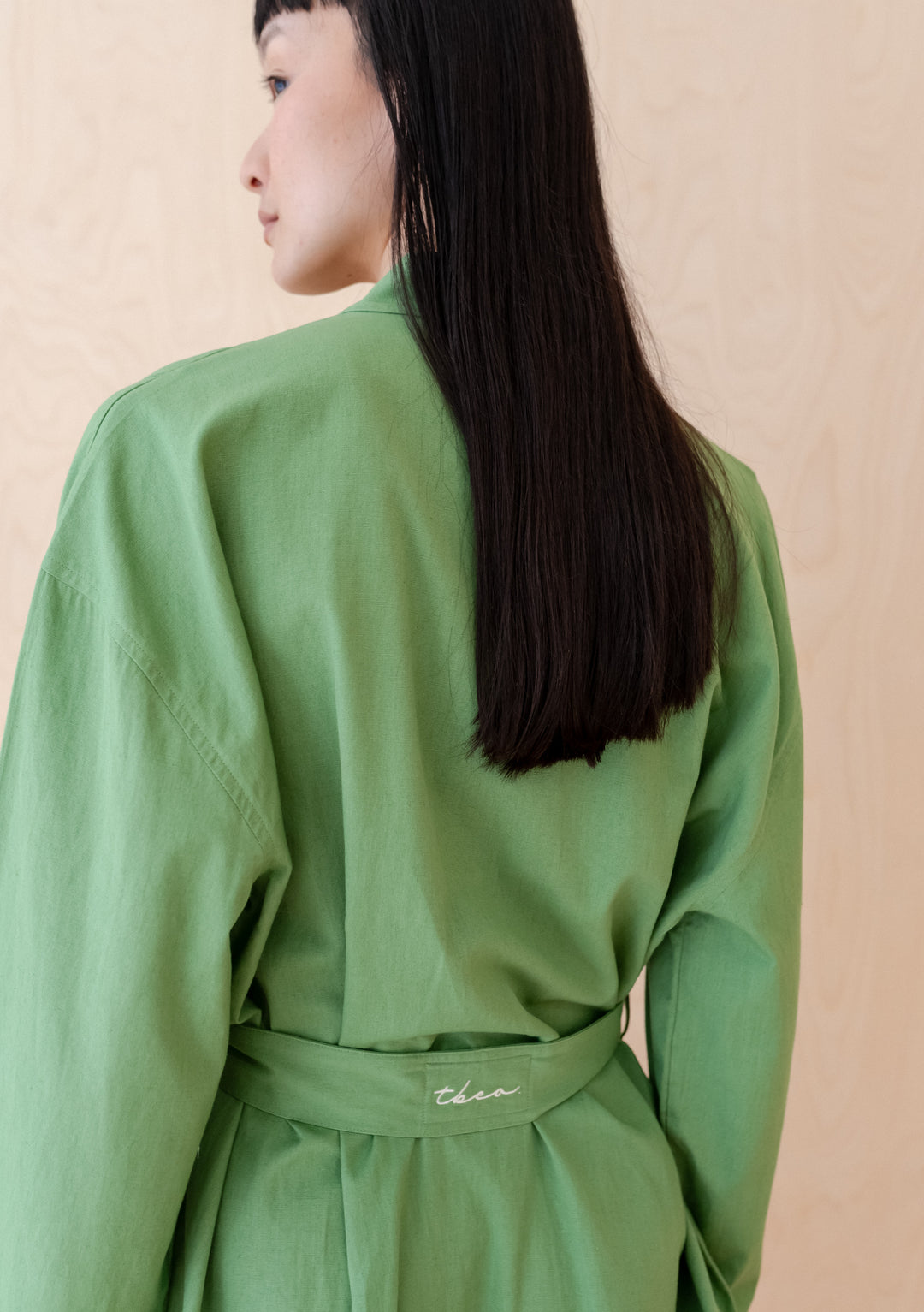 Side view of TBCo Cotton & Linen Robe in Green showing relaxed fit and sewn-in belt detail against neutral background