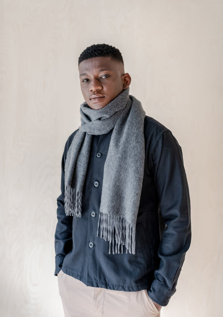 TBCo Men's Lambswool Scarf in Charcoal Melange styled casually with navy jacket, featuring soft texture and classic fringe detail