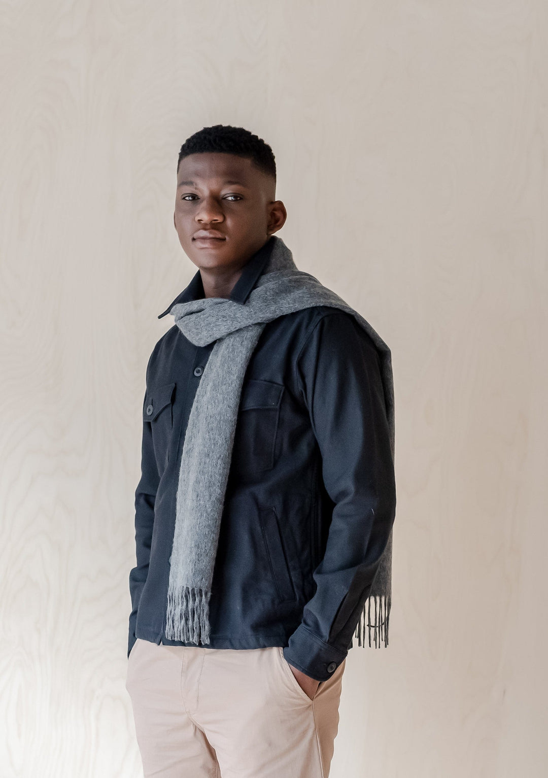 TBCo luxury charcoal melange cashmere scarf with fringe styled over navy jacket showing drape and texture detail