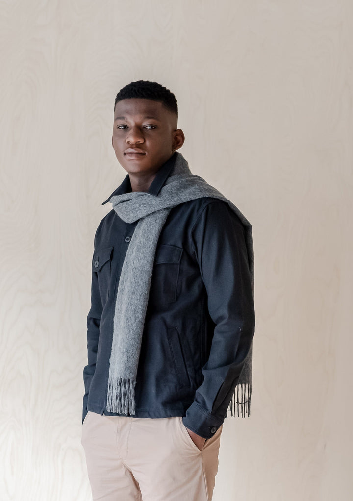 TBCo luxury charcoal melange cashmere scarf with fringe styled over navy jacket showing drape and texture detail
