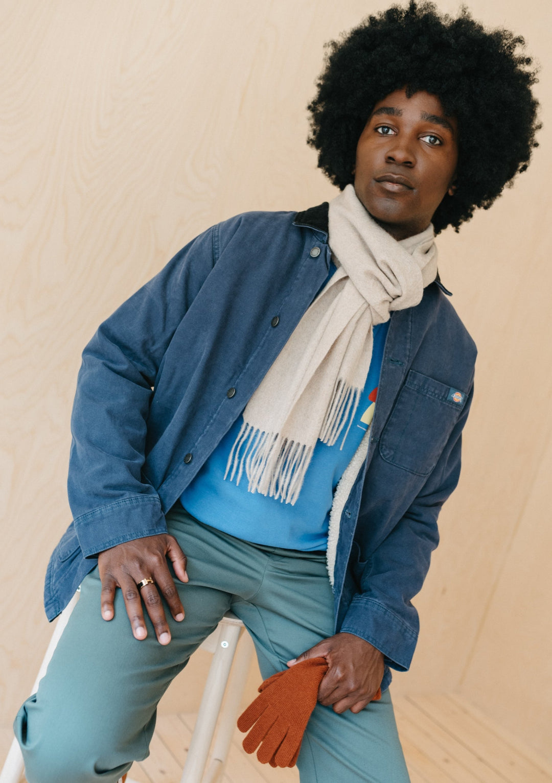 TBCo Men's Cashmere Scarf in Oatmeal Melange styled with denim jacket and mint trousers against beige backdrop