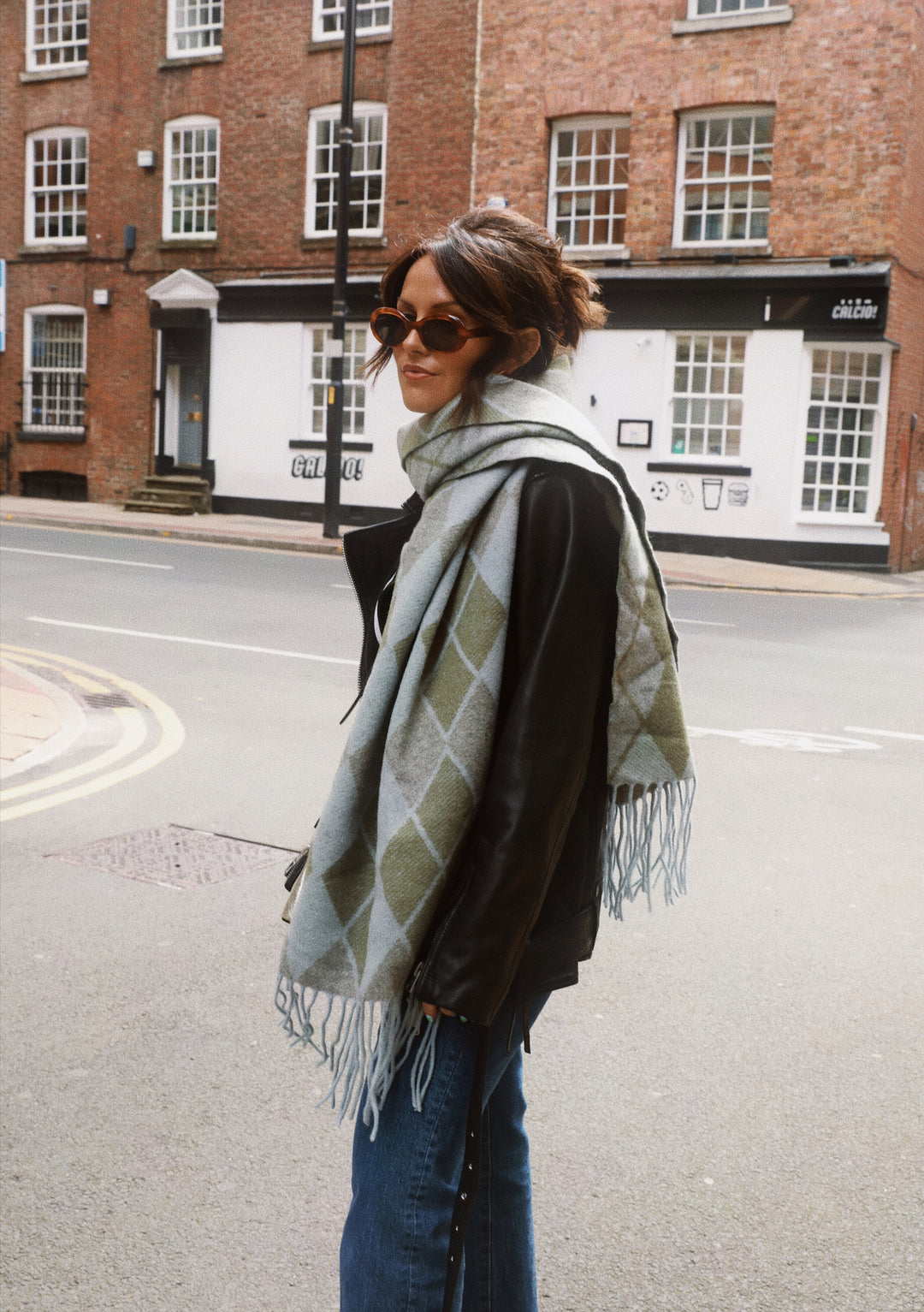 TBCo x Amy Bell Dunnottar Scarf styled with leather jacket and sunglasses on Edinburgh street, showcasing grey argyle pattern