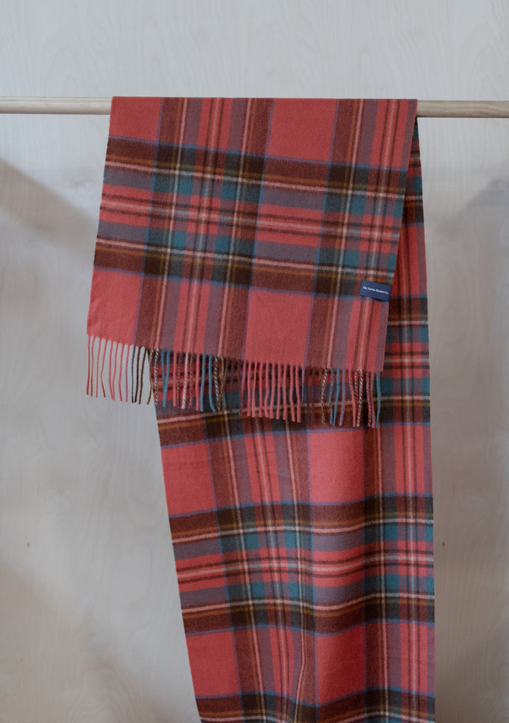 TBCo Lambswool Oversized Scarf in Stewart Royal Antique Tartan draped over wooden rail showing red and blue plaid pattern with fringe