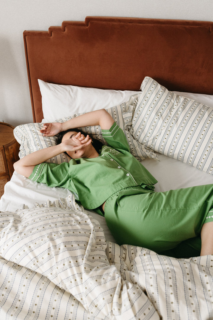 Relaxing on a bed dressed in TBCo bedding set featuring patterned pillowcases and duvet cover with a rust headboard