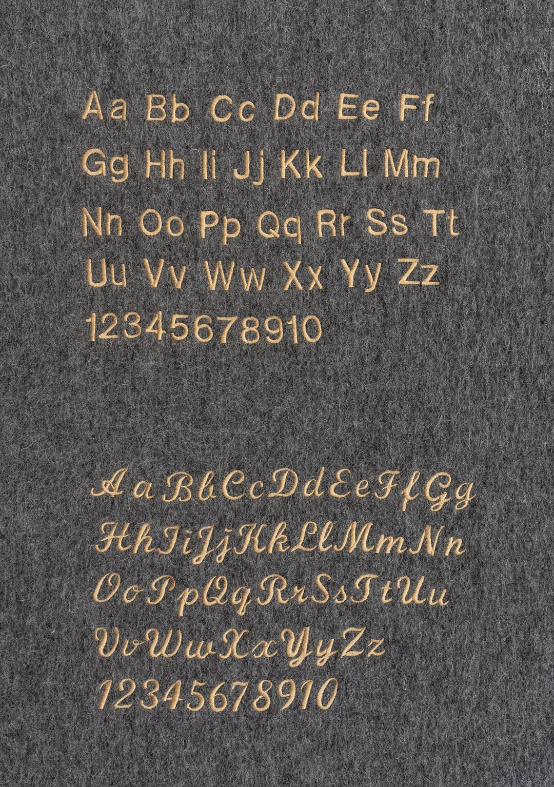 Custom embroidery options on grey fabric showcasing letter styles for the Merino Wool Triangle Scarf in Blue & Brown Stripe by TBCo