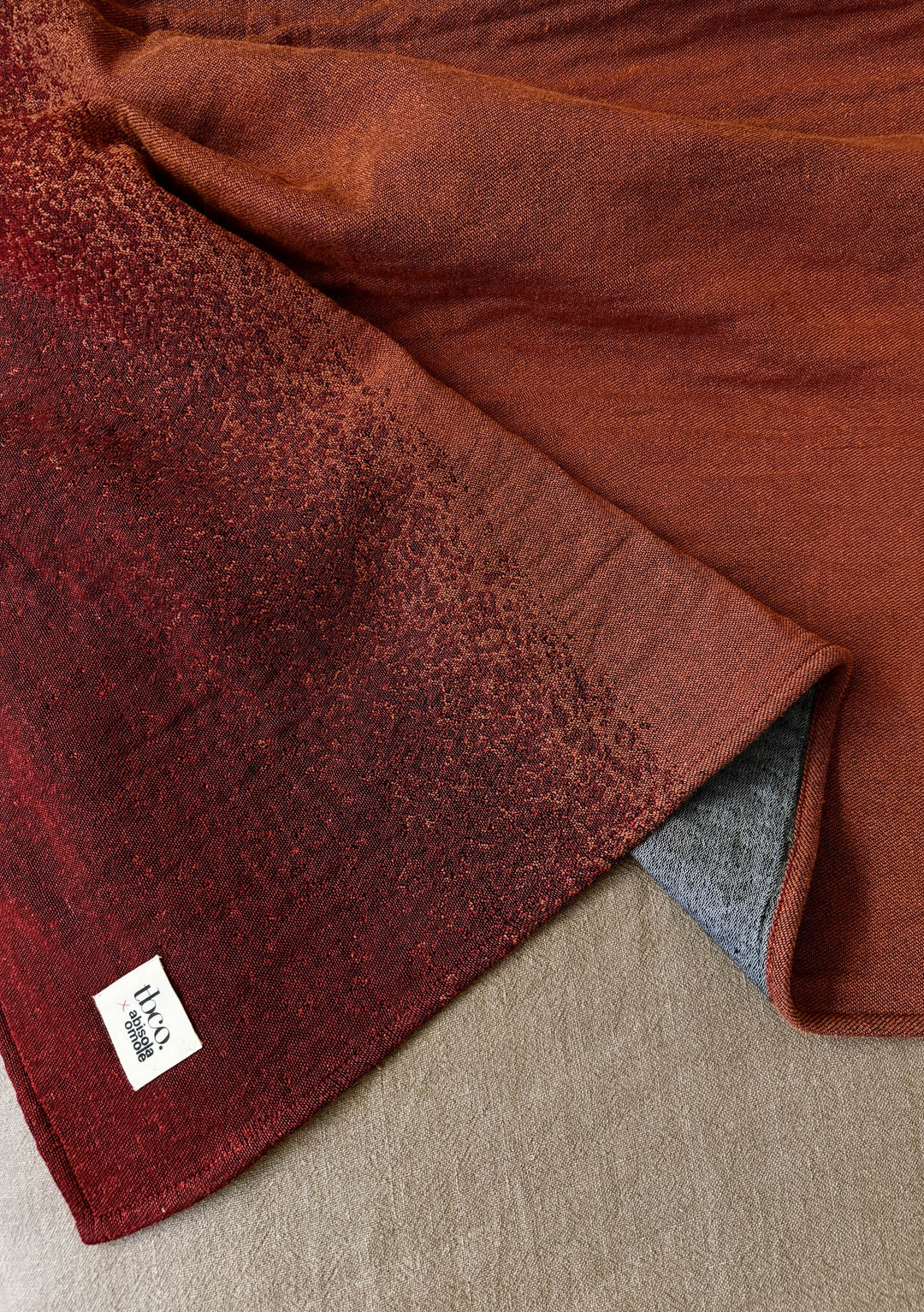 TBCo x Abisola Omole Hues Cotton Throw featuring gradient design in rich burgundy and charcoal tones, displaying luxurious texture