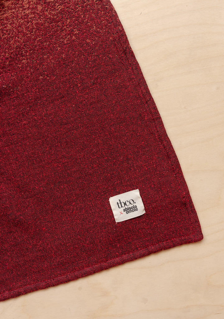 TBCo x Abisola Omole Hues Cotton Throw featuring gradient burgundy tones and charcoal, with signature TBCo label detail