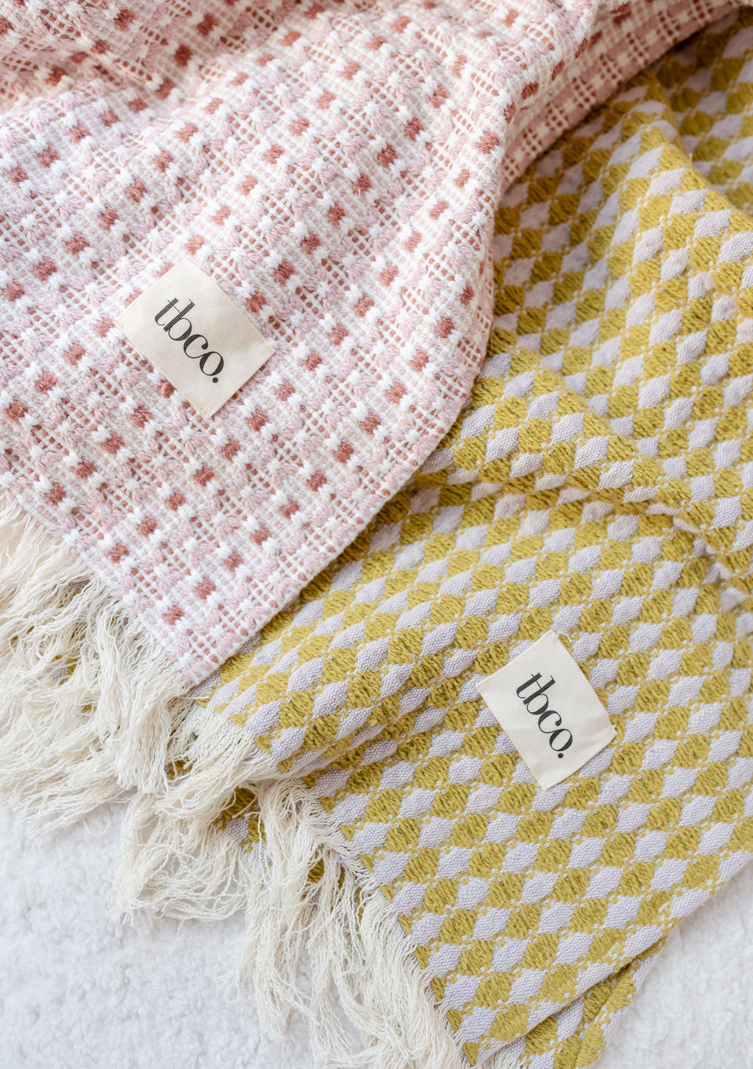 Textured cotton throw blanket in olive argyle pattern by TBCo featuring geometric weave and fringed edges, photographed with fabric detail