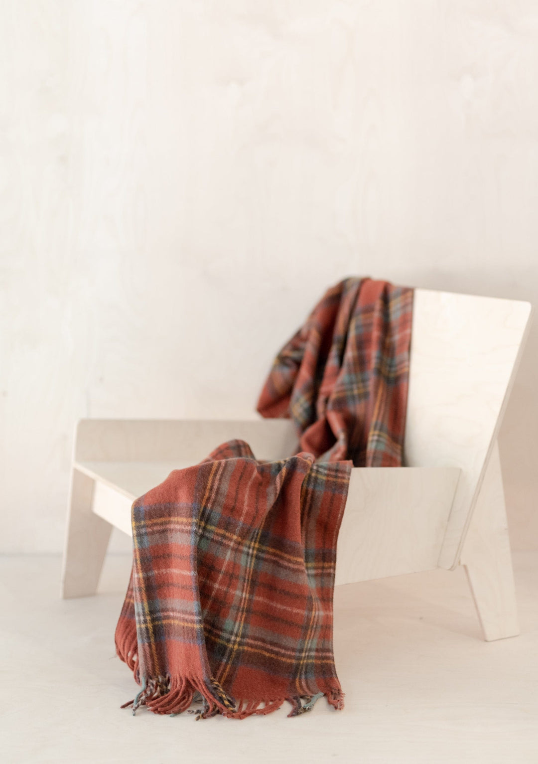 TBCo recycled wool small blanket in Stewart Royal Antique tartan pattern draped over white modern chair with fringe detail