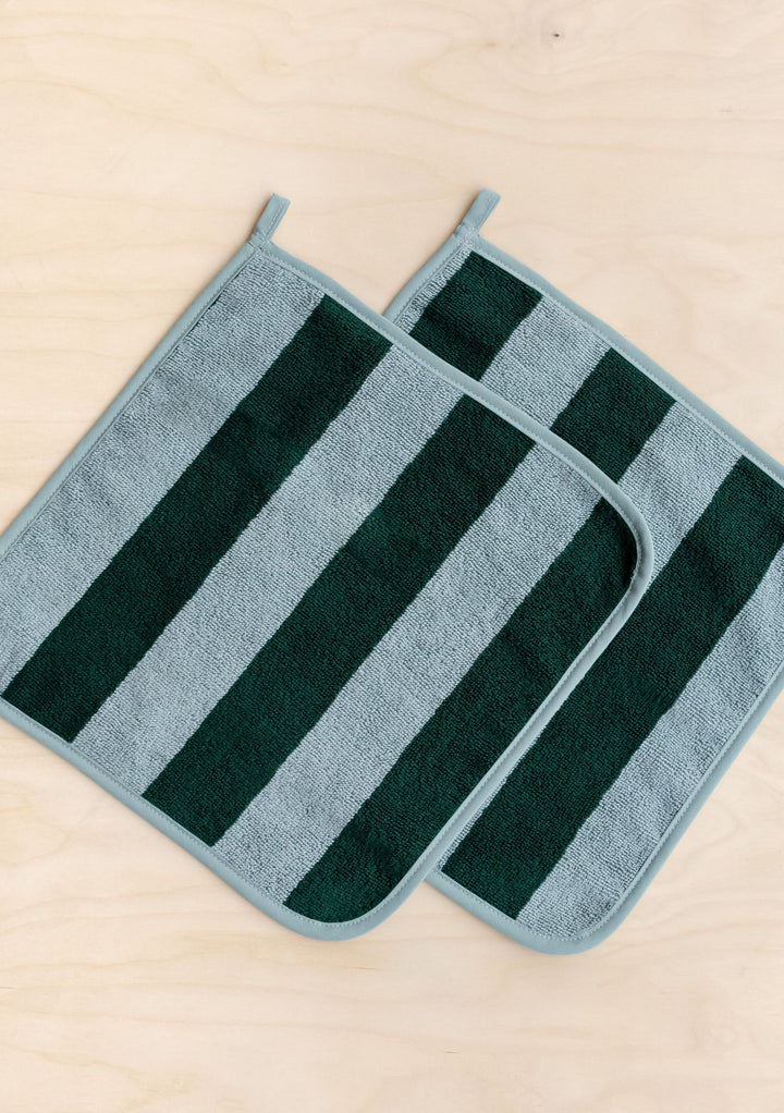 Two green striped Terry Cotton Face Cloths Set of 2 in Green Stripe by TBCo laid flat on wooden surface