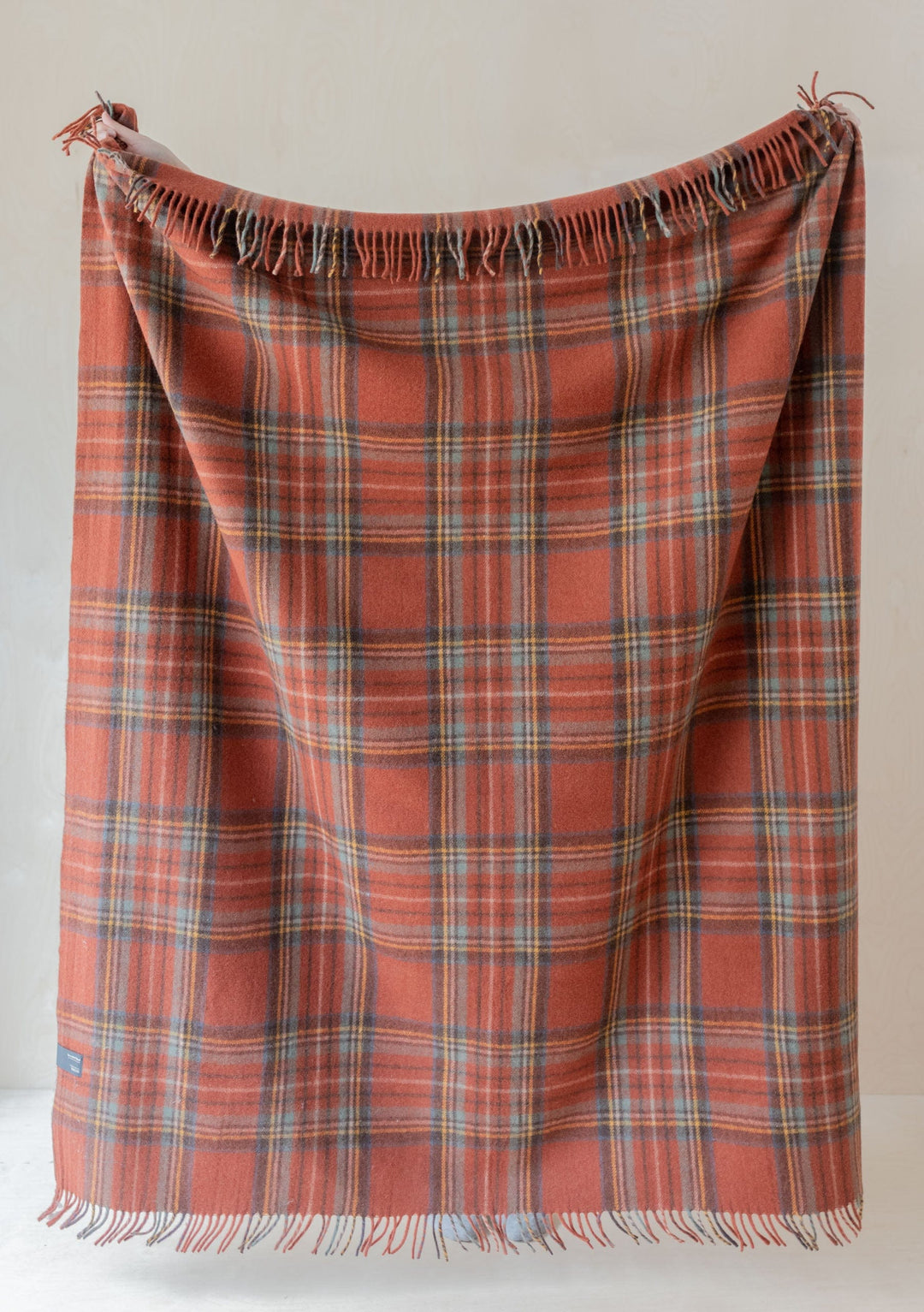 TBCo Recycled Wool Blanket in Stewart Royal Antique Tartan, displaying salmon-pink plaid pattern with fringed edges on cream backdrop