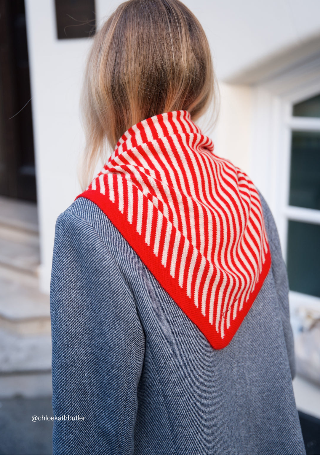 TBCo Large Merino Triangle Scarf in red and cream stripes styled over grey coat, showing diagonal drape and pattern details