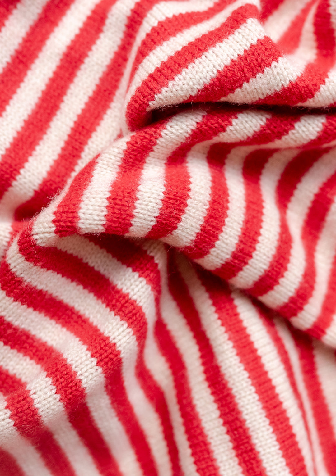 TBCo Large Merino Triangle Scarf featuring red and cream stripes, knitted in soft merino wool with distinctive diagonal pattern