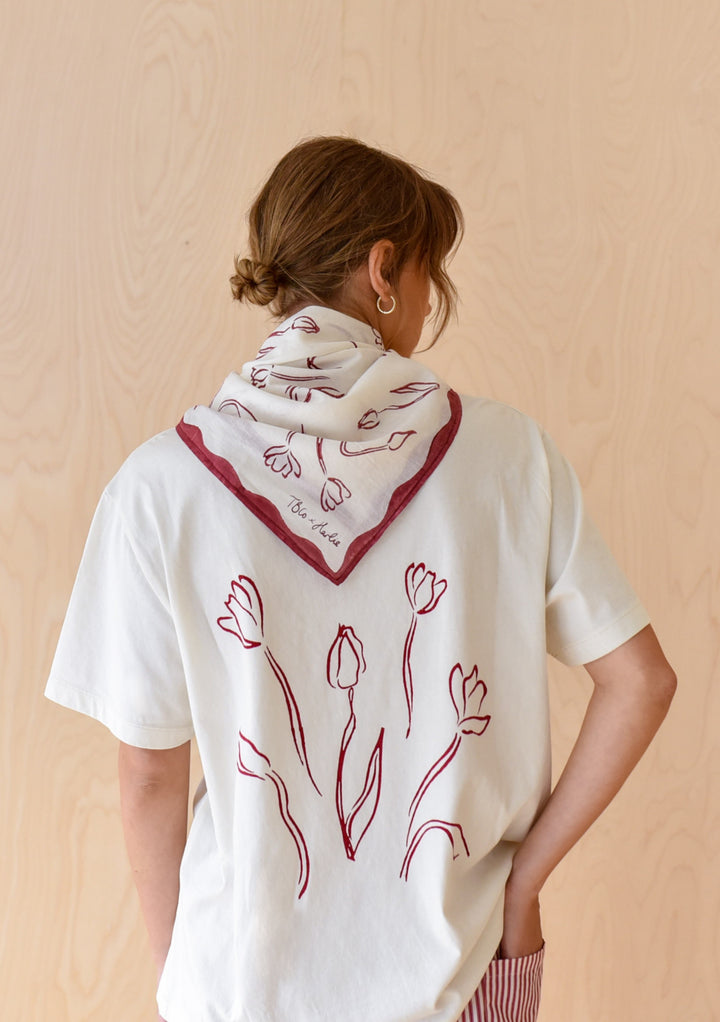 Back view of The Artist Series TBCo x Harlie Briggs Cotton T-Shirt featuring red tulip sketches, paired with a matching bandana, embodying casual, artistic style.