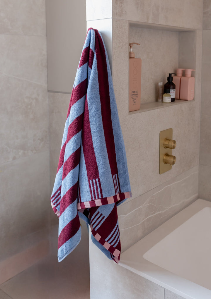 Luxurious TBCo Cotton Towels in Blue Stripe with burgundy stripes and checkered pattern hanging in modern bathroom