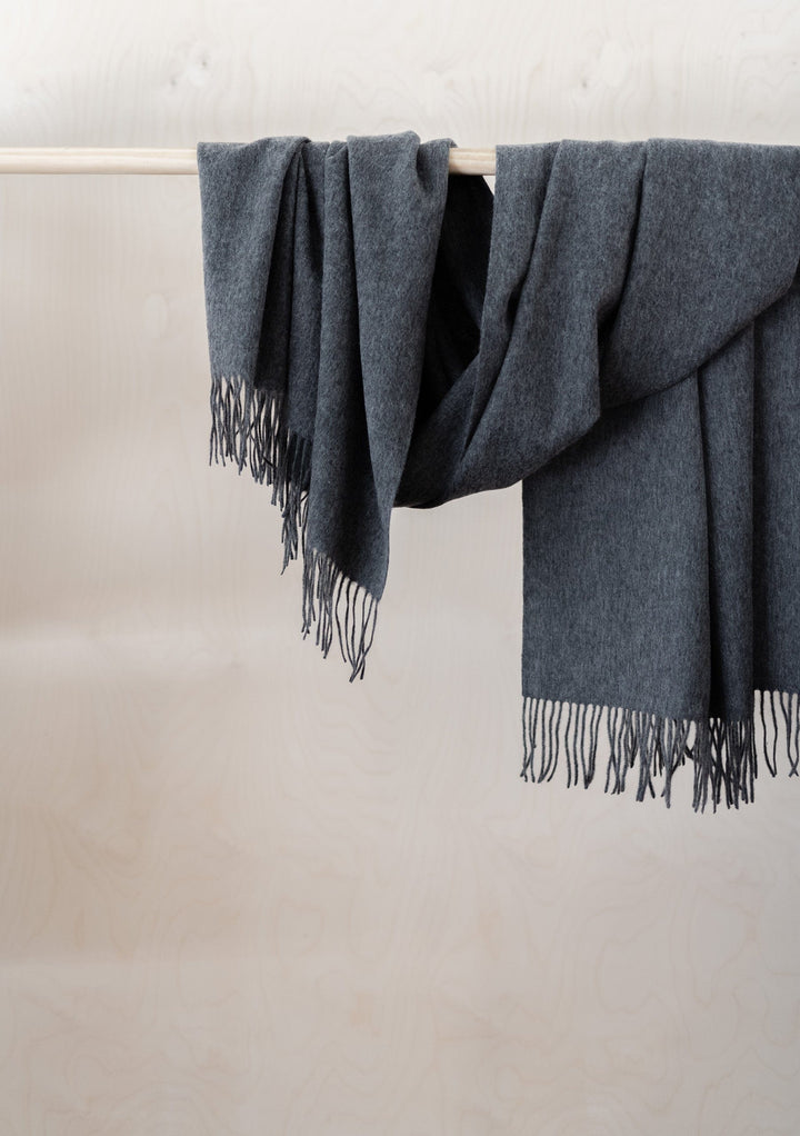 TBCo Lambswool Blanket Scarf in Charcoal Melange draped elegantly over rail, showcasing soft texture and fringed edges