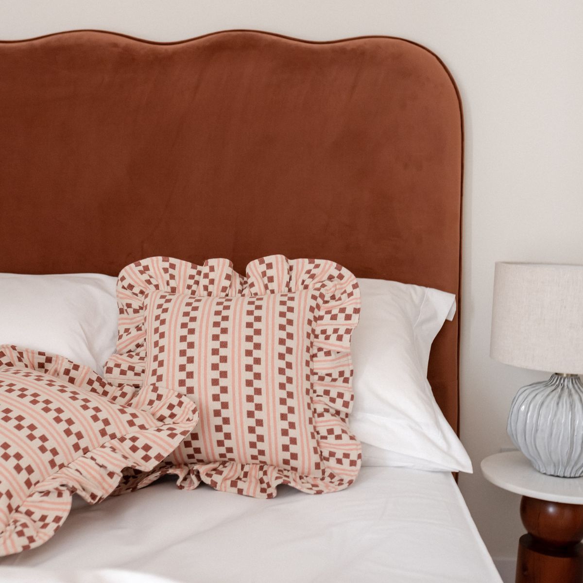 TBCo Pink Geometric Cushions styled on a bed. The perfect setting for relaxed and fashionable home styling. 