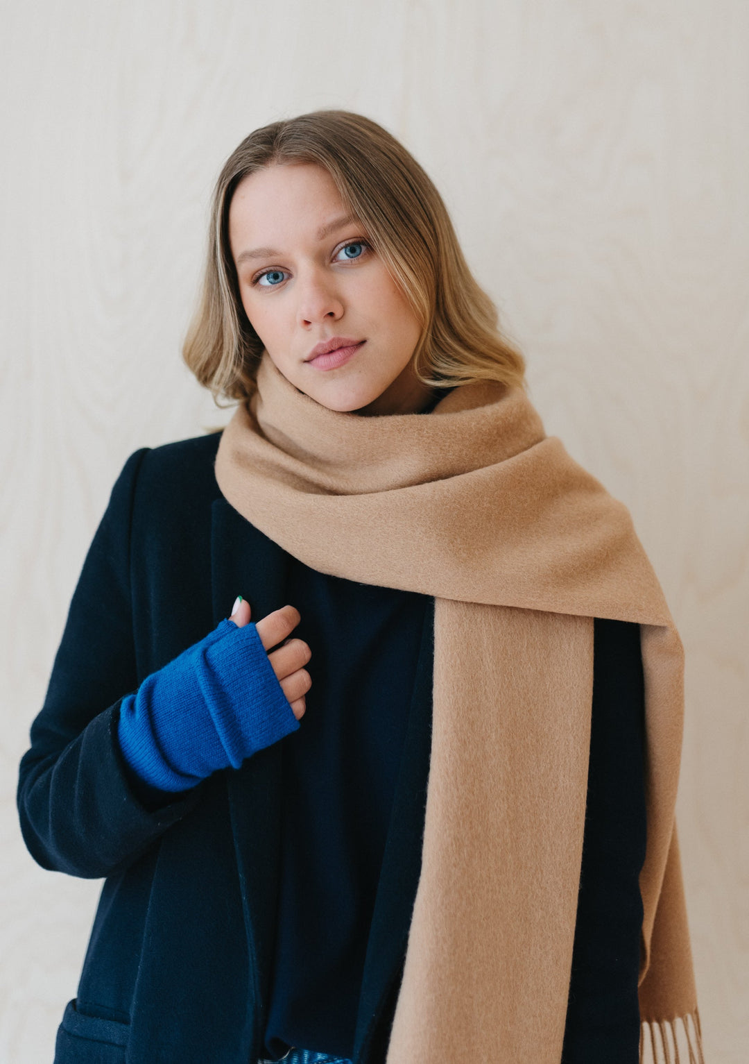 Soft camel TBCo lambswool scarf styled with navy jumper and bright blue gloves against white background