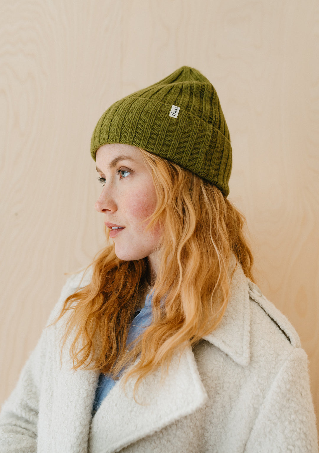 TBCo olive cashmere and merino wool beanie with ribbed texture, shown in profile against neutral background