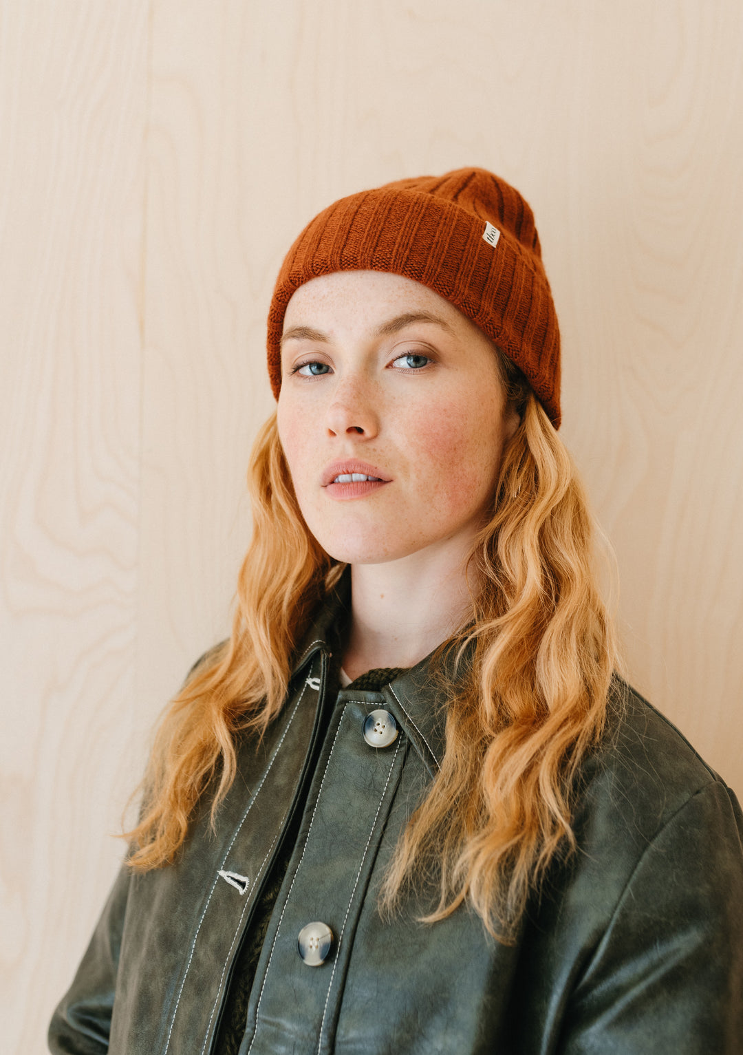 TBCo rust-coloured cashmere and merino wool beanie with ribbed texture shown on model against neutral background