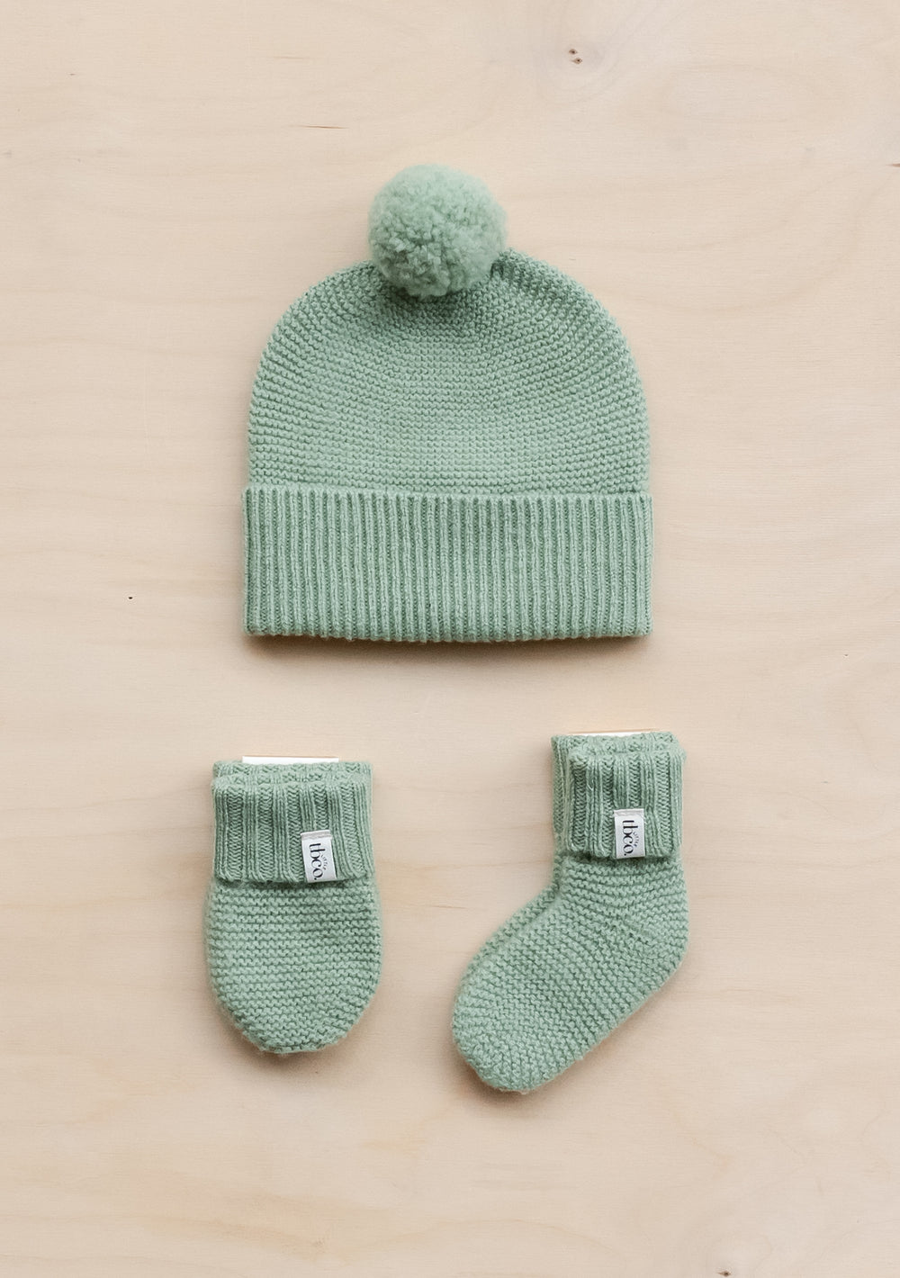 TBCo Merino Wool Baby Accessories Bundle in pistachio green featuring knitted beanie with pom-pom, mittens and socks