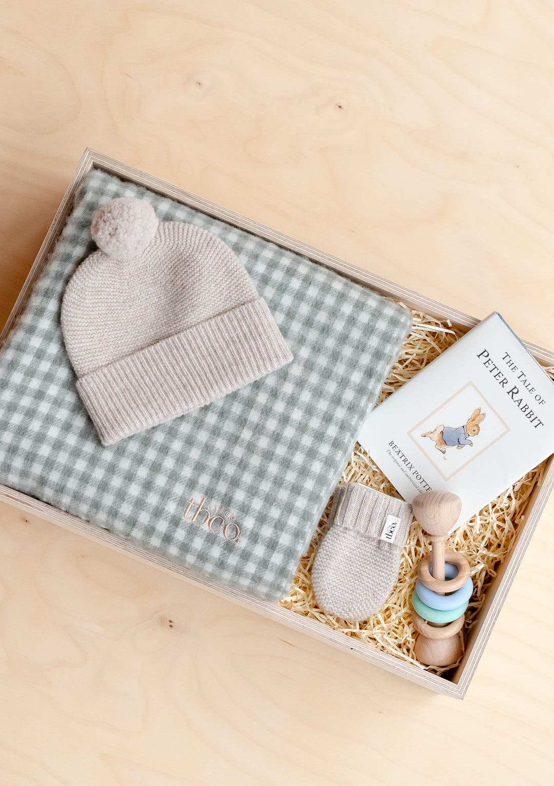 TBCo Baby Gift Box featuring grey knit beanie, gingham blanket, Peter Rabbit book and wooden rattle in custom presentation box