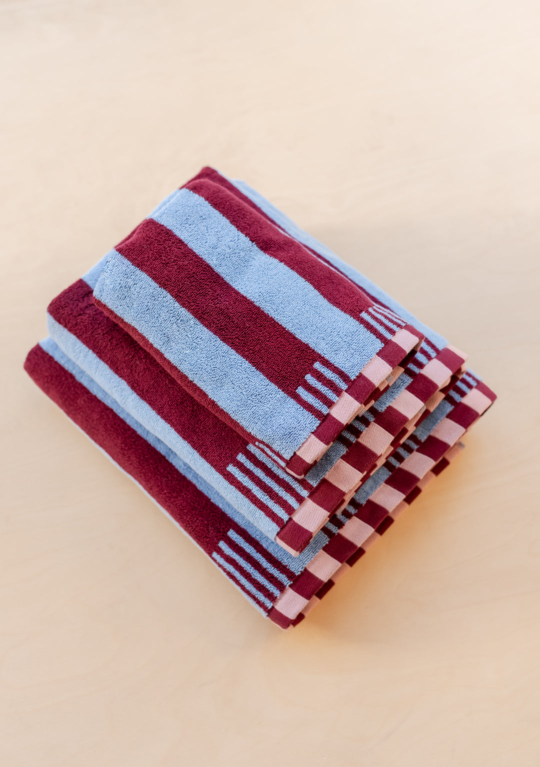 TBCo Cotton Towels in Blue Stripe with burgundy stripes and checkered border, folded neatly showing plush texture