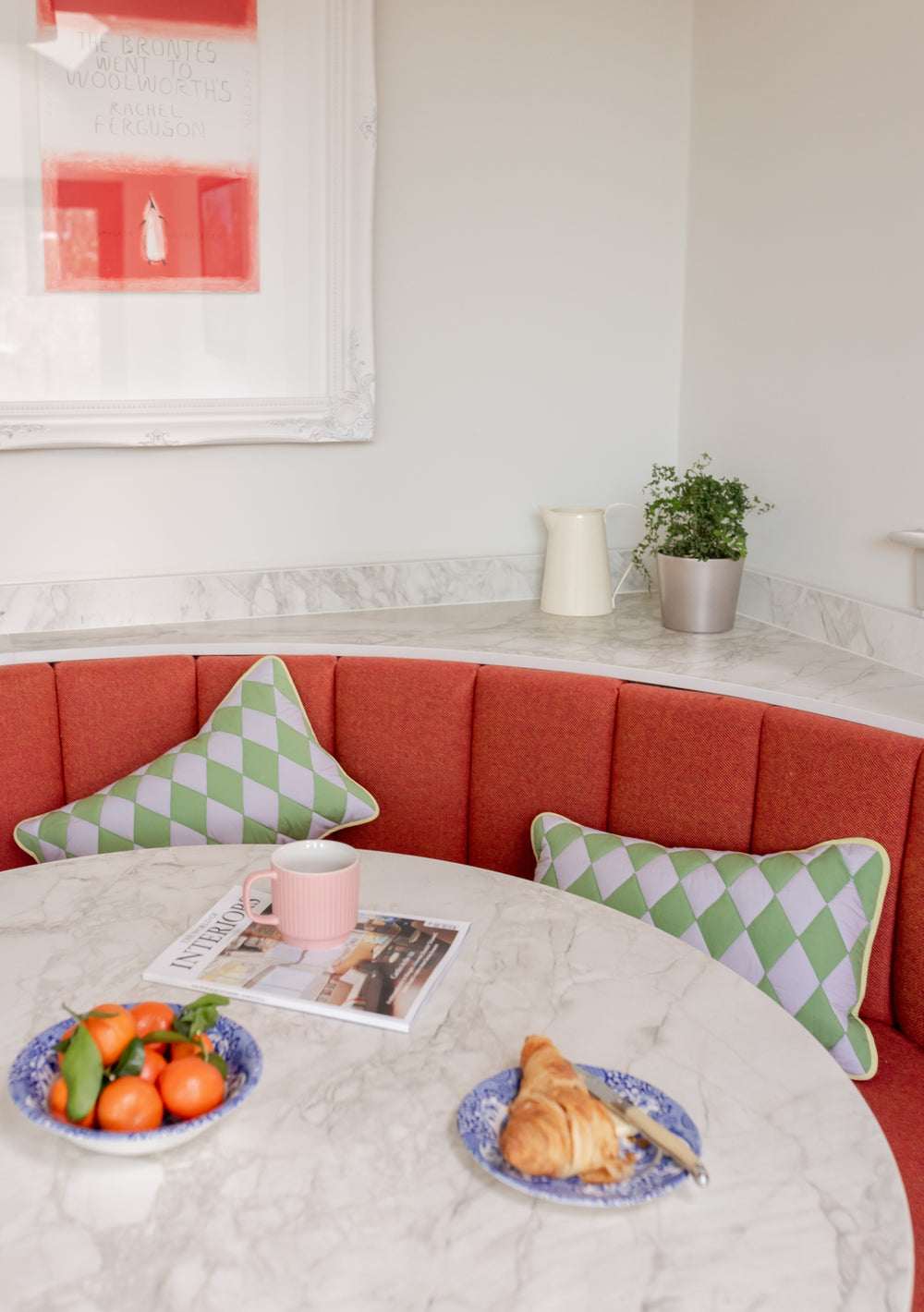 TBCo Green Argyle Cotton Cushion Cover styled on curved coral banquette with marble table, breakfast setting with fresh pastries