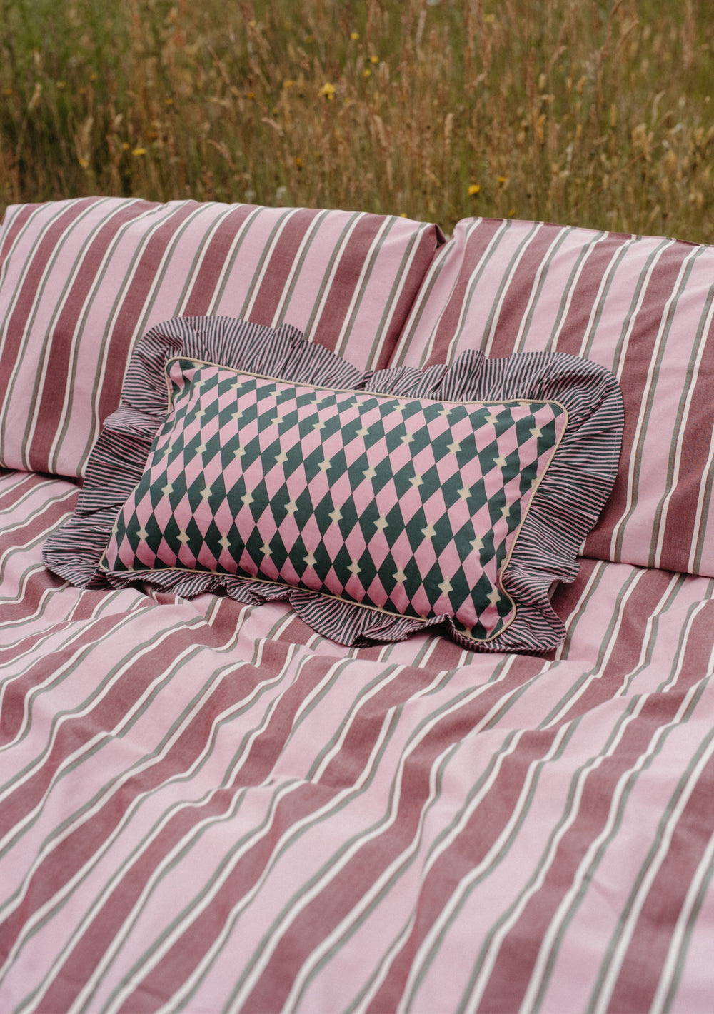 Cotton Cushion Cover in Pink Harlequin by TBCo, featuring reversible pink and green diamond and stripe patterns.