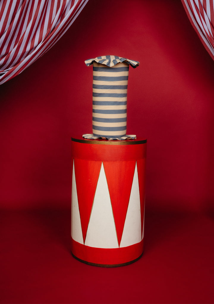 TBCo Cotton Cushion Cover in Navy Stripe with frilled edges, displayed on a circus-themed pedestal with a red and white backdrop, showcasing its elegant design.