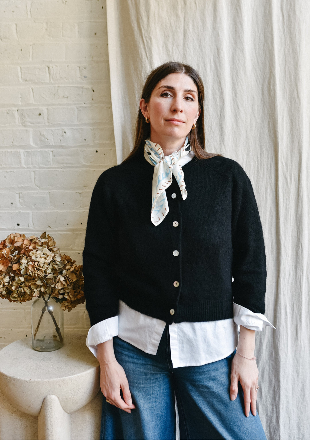TBCo Chiara Perano Artist Series Cotton Square Triangle Neck Scarf  by a the artist standing in front of a white sheet background beside a side table with flowers in a vase