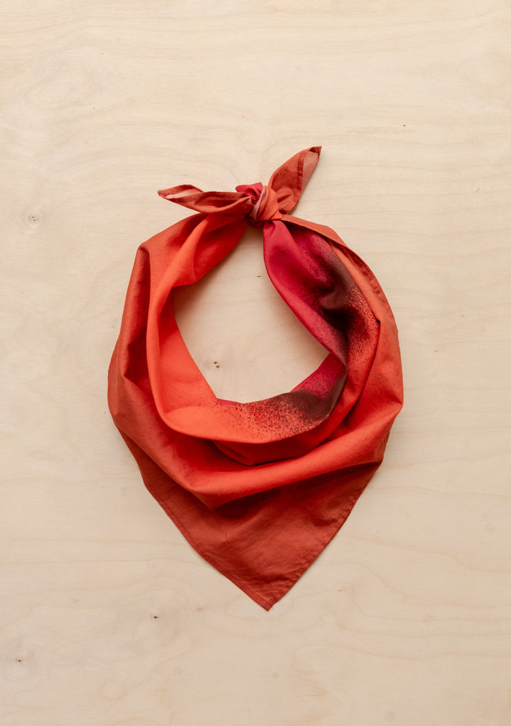 Sample Sale TBCo x Abisola Omole Hues Cotton Scarf in warm red tones tied in a knot on a light wooden surface