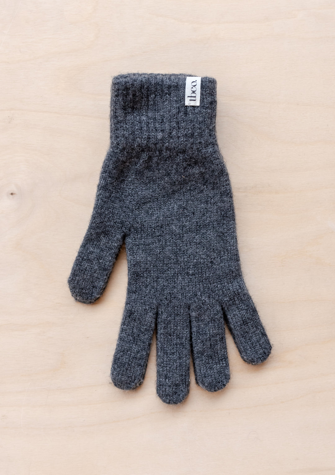 TBCo Cashmere & Merino Gloves in charcoal melange shown flat, displaying knitted texture and classic five-finger design with brand label