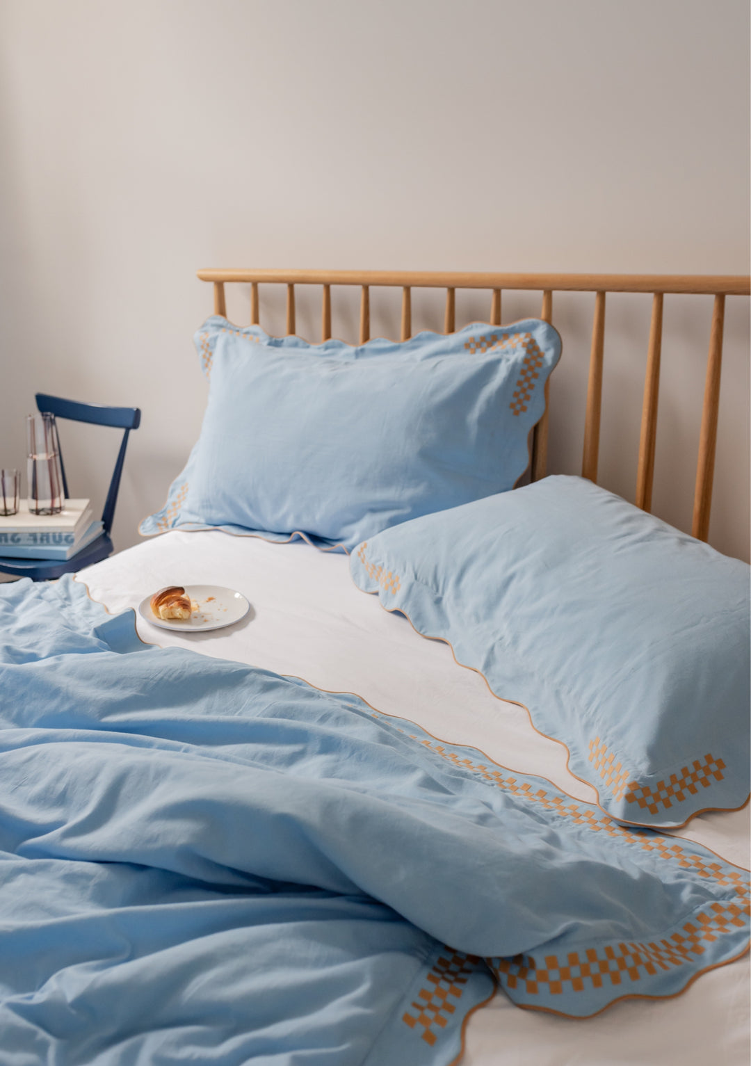 TBCo Cotton & Linen Duvet Cover in blue with camel checkerboard embroidery and scalloped edges on wooden bed frame