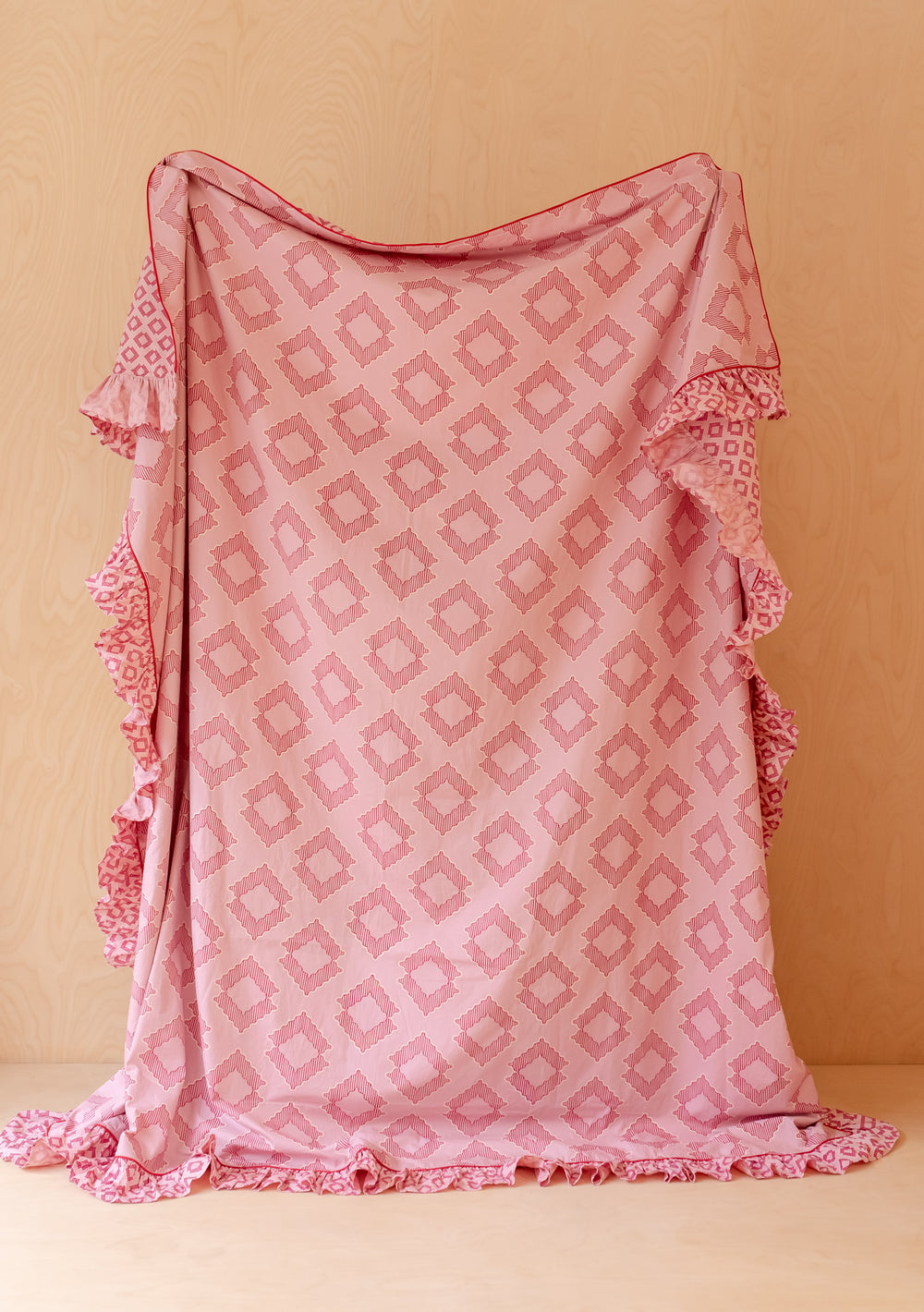 TBCo Cotton Duvet Cover & Pillowcases Set in Pink Diamond with soft pink geometric print and ruffled edges displayed fully draped