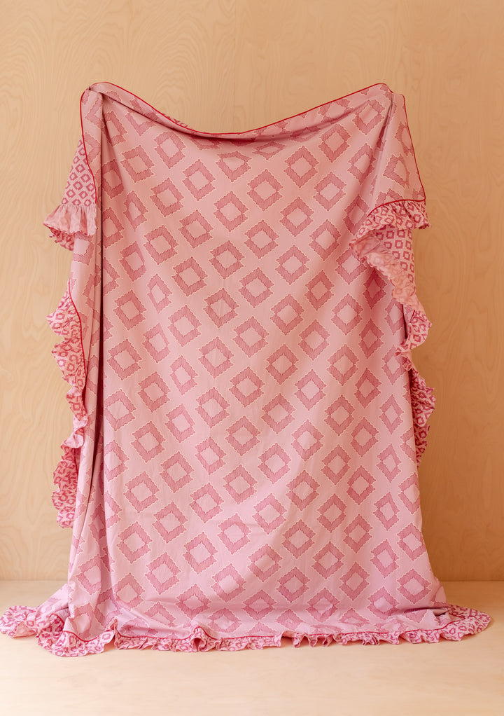 TBCo Cotton Duvet Cover & Pillowcases Set in Pink Diamond with soft pink geometric print and ruffled edges displayed fully draped