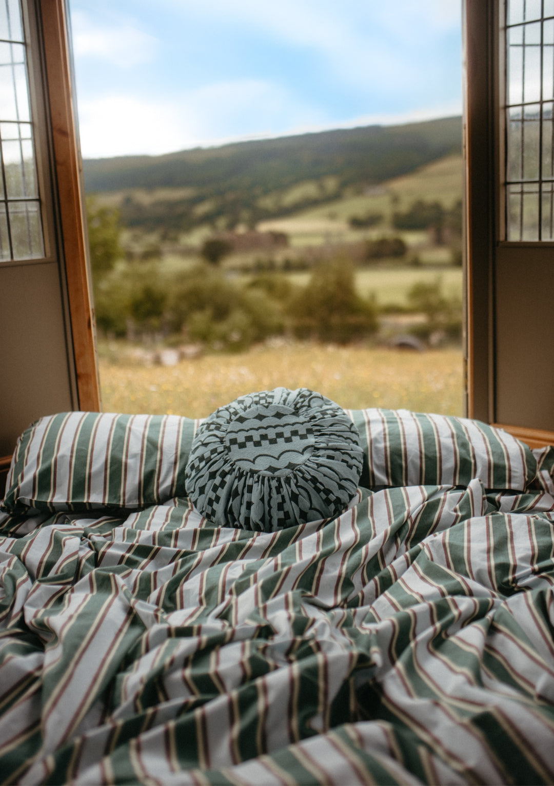 TBCo Cotton Duvet Cover in Blue Stripe with tailored stripes on bed by open window showing countryside view