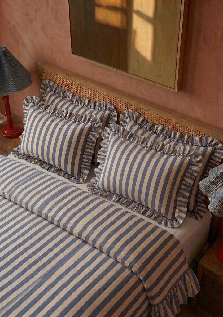 Pair of Cotton Pillowcases in Navy Stripe by TBCo with ruffled edges on soft cotton fabric in cosy bedroom setting