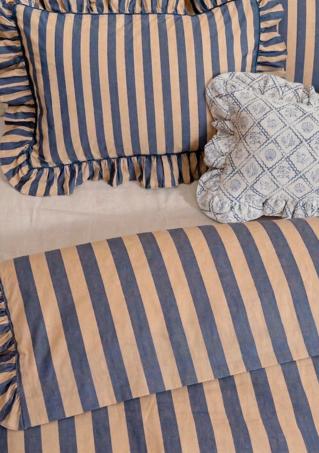 Pair of Cotton Pillowcases in Navy Stripe by TBCo featuring soft navy and beige stripes with ruffled edges on relaxed bedding setting