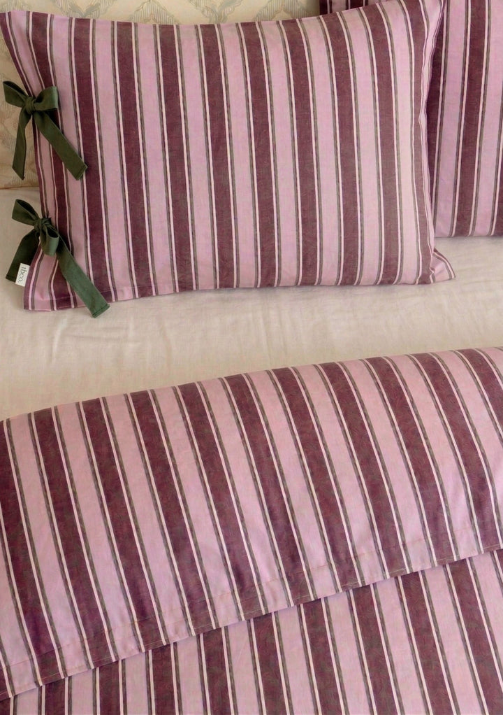 Close-up of TBCo Cotton Duvet Cover & Pillowcases Set in Pink Stripe with soft pink and burgundy stripes and green ribbon ties