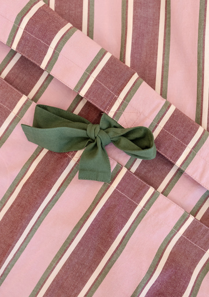Close-up of pink stripe Cotton Duvet Cover by TBCo featuring green tie closures and breathable cotton poplin fabric.