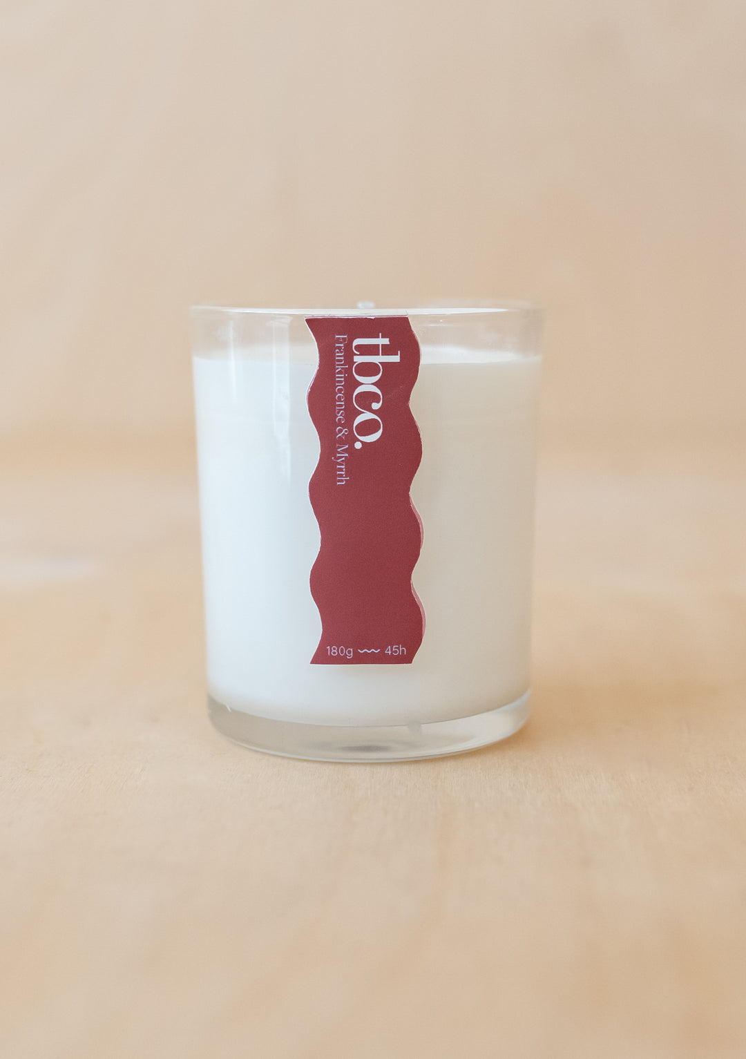 TBCo Frankincense & Myrrh Candle in clear glass with red label, offering 45 hours burn time and soothing festive fragrance